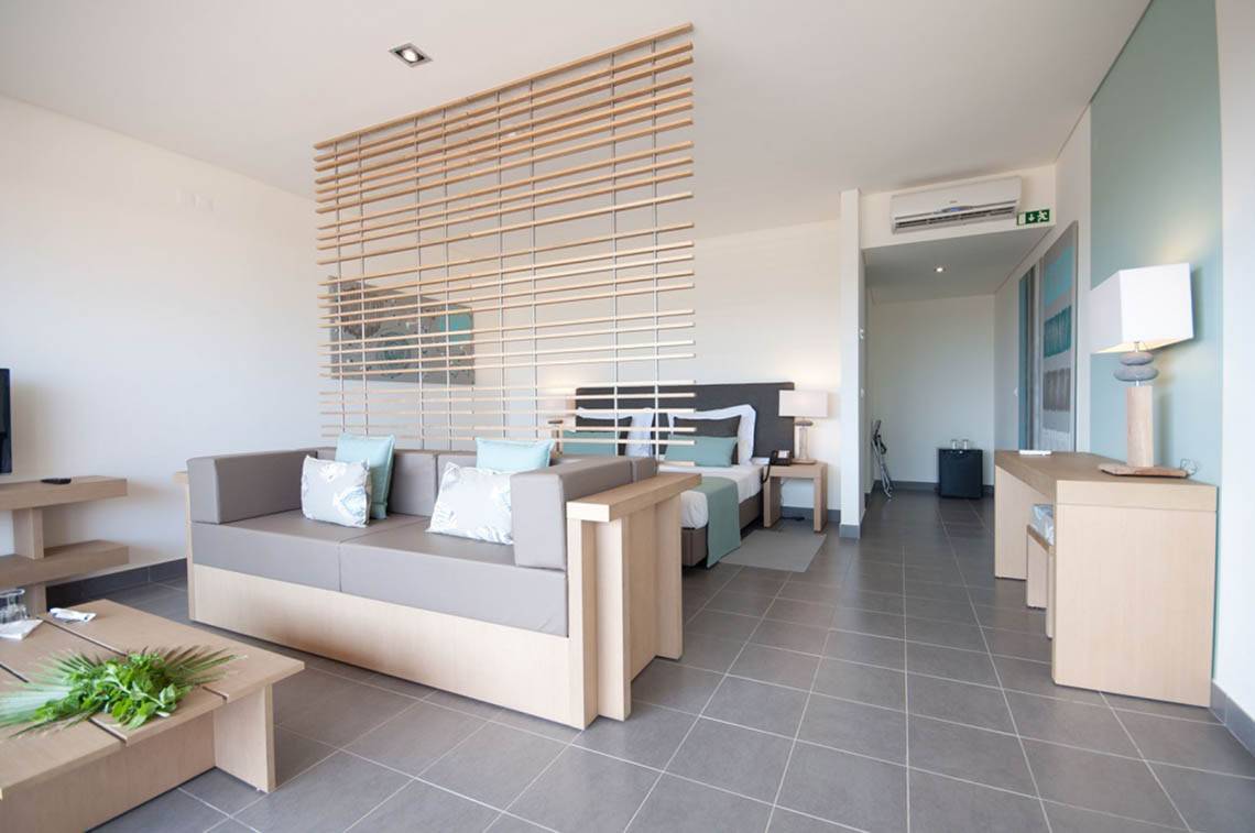 Modernes Hotelzimmer im Oasis Salinas Sea mit Bett, Sofa, Tisch und Klimaanlage.