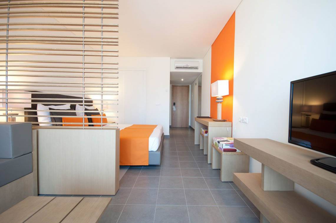 Schlafzimmer im Oasis Salinas Sea Hotel mit Bett, Fernseher und modernen Möbeln.