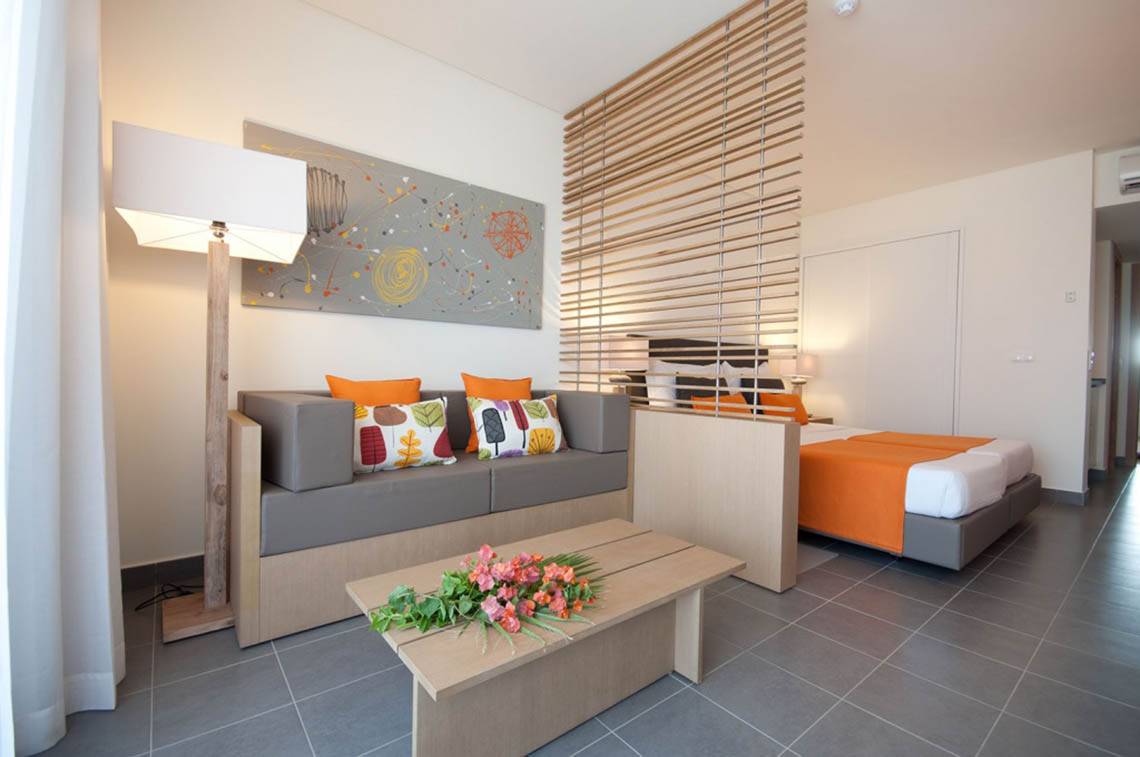 Innenansicht eines Zimmers im Oasis Salinas Sea Hotel mit einem Sofa, Tisch und Bett.