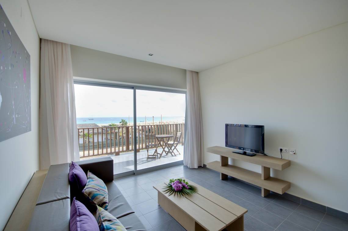 Wohnzimmer mit Meerblick im Oasis Salinas Sea Hotel mit Fernseher und Couch.