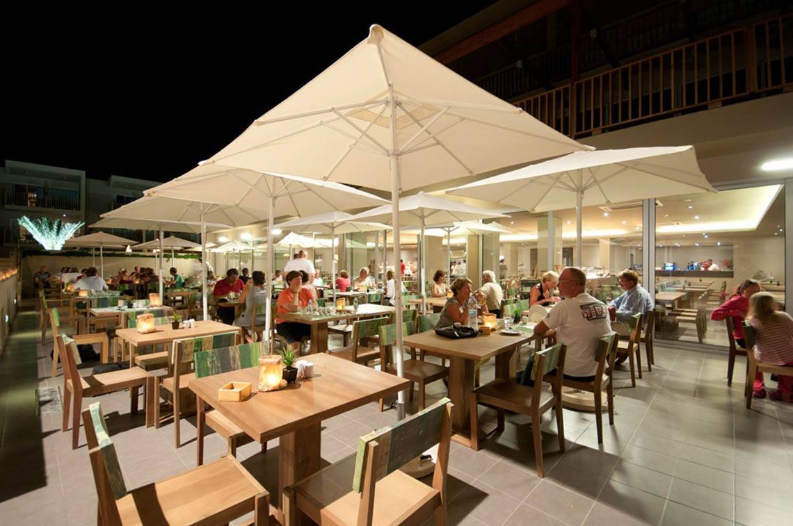 Abendstimmung im Restaurant des Oasis Salinas Sea Hotels mit Gästen unter weißen Sonnenschirmen.