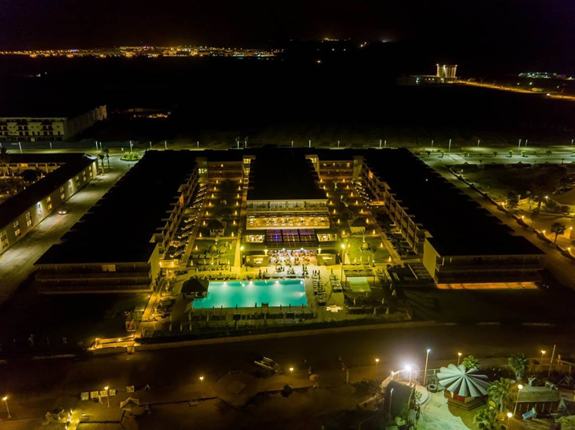 Abendansicht des Oasis Salinas Sea Hotels mit beleuchtetem Swimmingpool und Gebäuden.