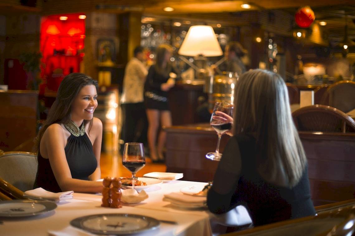 Zwei Frauen im Restaurant Al Ain Rotana mit Weinglas unterhalten sich.