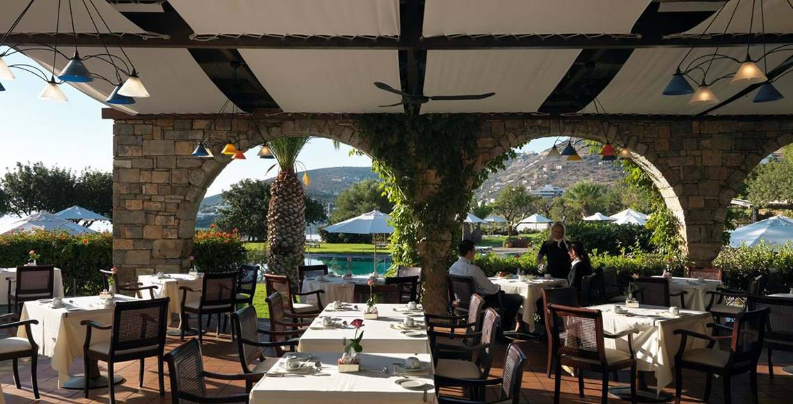 Restaurant-Terrasse des Elounda Beach Hotel & Villas mit Gästen und Blick auf den Pool.