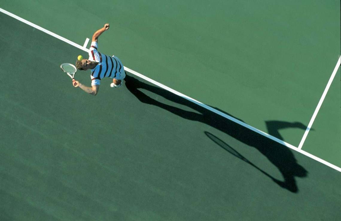 Tennisspieler mit Schläger auf Tennisplatz beim Aufschlag