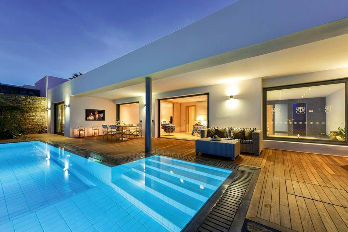 Außenbereich des Elounda Beach Hotel & Villas mit Swimmingpool und Holzterrasse.