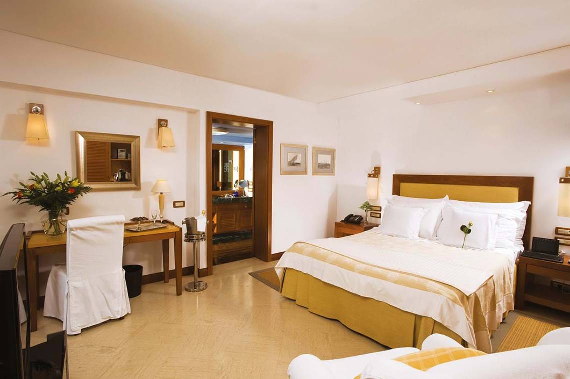 Schlafzimmer im Elounda Beach Hotel & Villas mit Bett, Schreibtisch und Möbeln.