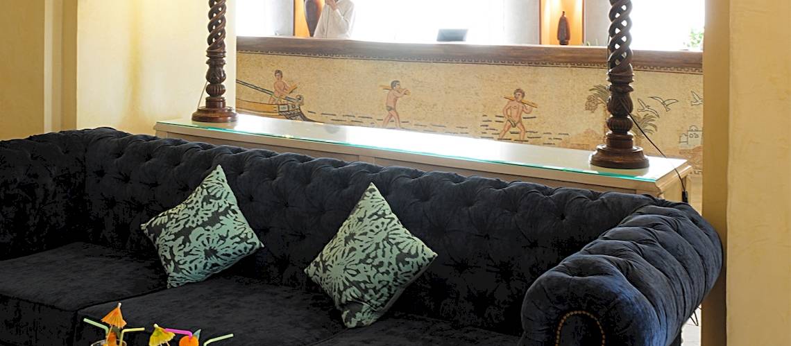 Lobby des Djerba Resorts mit schwarzem Sofa, zwei grünen Kissen und einer Glastheke.