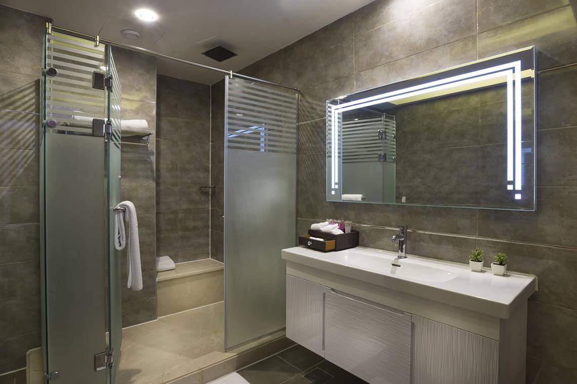 Badezimmer des Pickalbatros Aqua Blu Resort - Sharm mit Duschkabine, Spiegel und Waschbecken.
