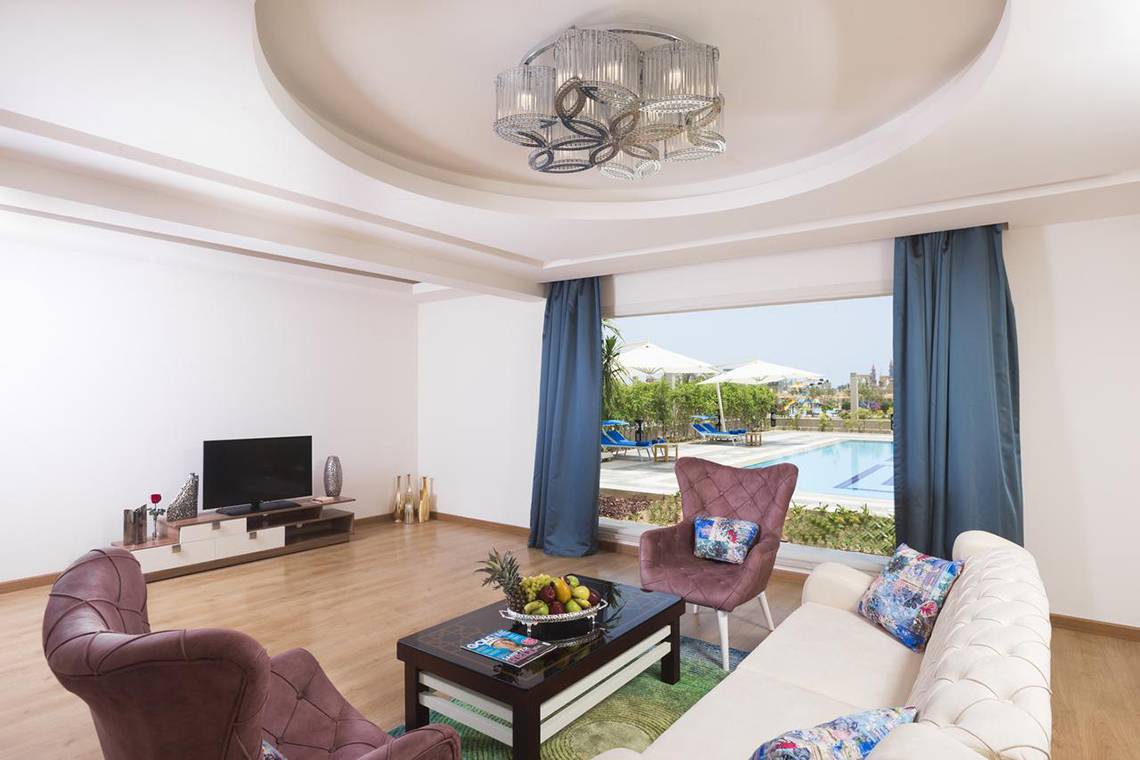 Innenansicht des Wohnzimmers im Pickalbatros Aqua Blu Resort mit moderner Einrichtung und Blick auf den Pool.