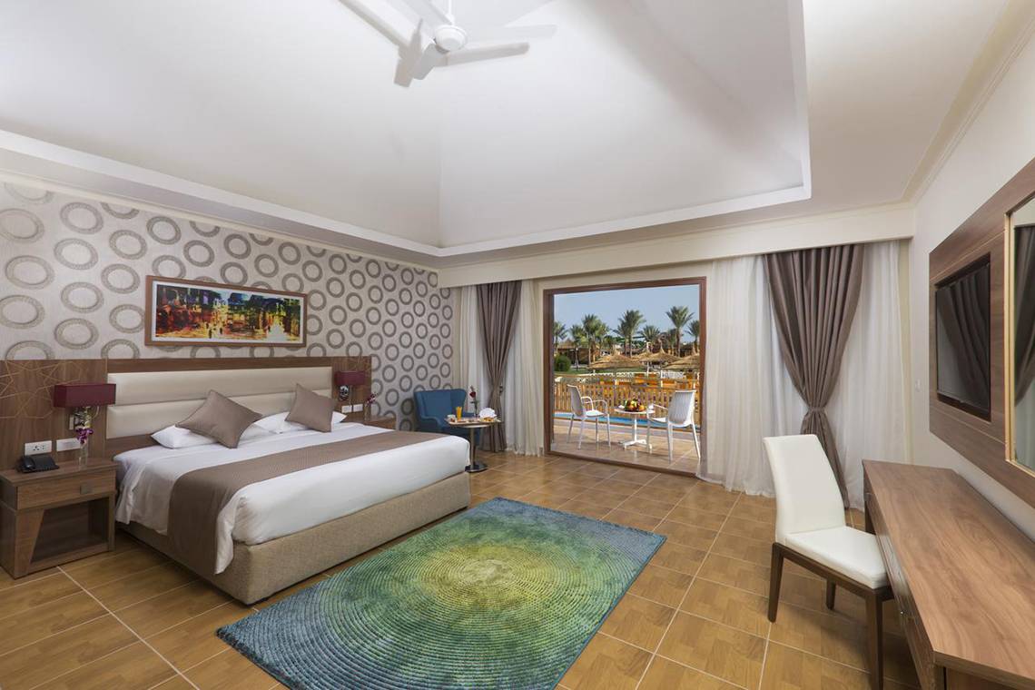 Ein modernes Hotelzimmer im Pickalbatros Aqua Blu Resort mit einem Bett, einem Teppich, einem Fernseher und einem Balkon.