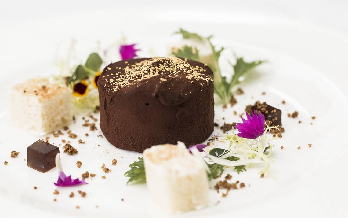 Schokoladenkuchen mit Golddekor und Beilagen auf weißem Teller