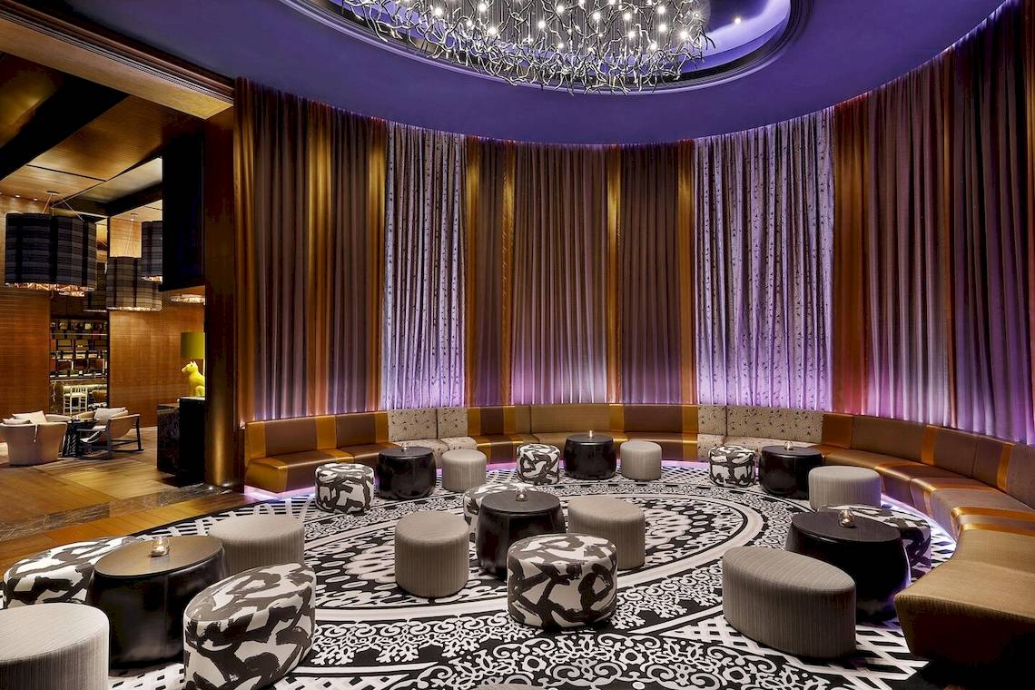 Loungebereich der Lobby im W Muscat Hotel mit runden Tischen und Sofas.