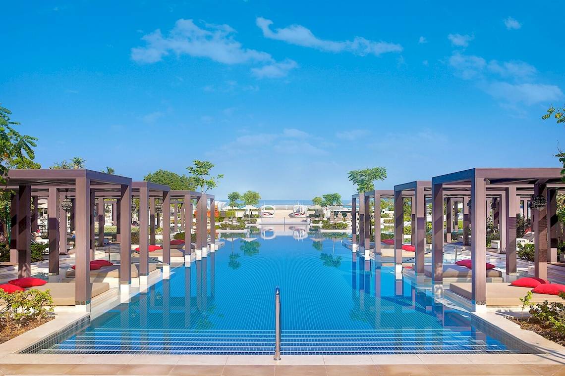 Infinity-Pool im W Muscat mit roten Kissen und blauem Wasser.