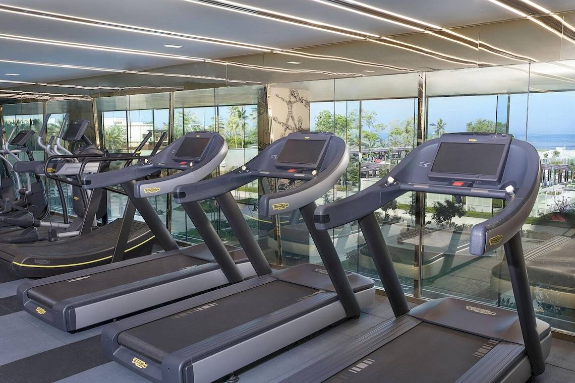 Fitnessstudio im W Muscat Hotel mit Blick auf das Meer und moderne Laufbändern.