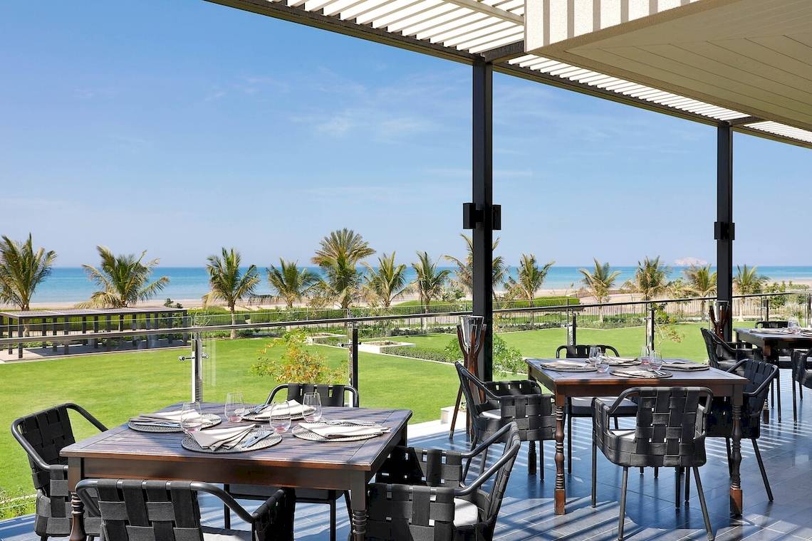 Außenterrasse des W Muscat Hotels mit Blick auf den Ozean und die Palmen