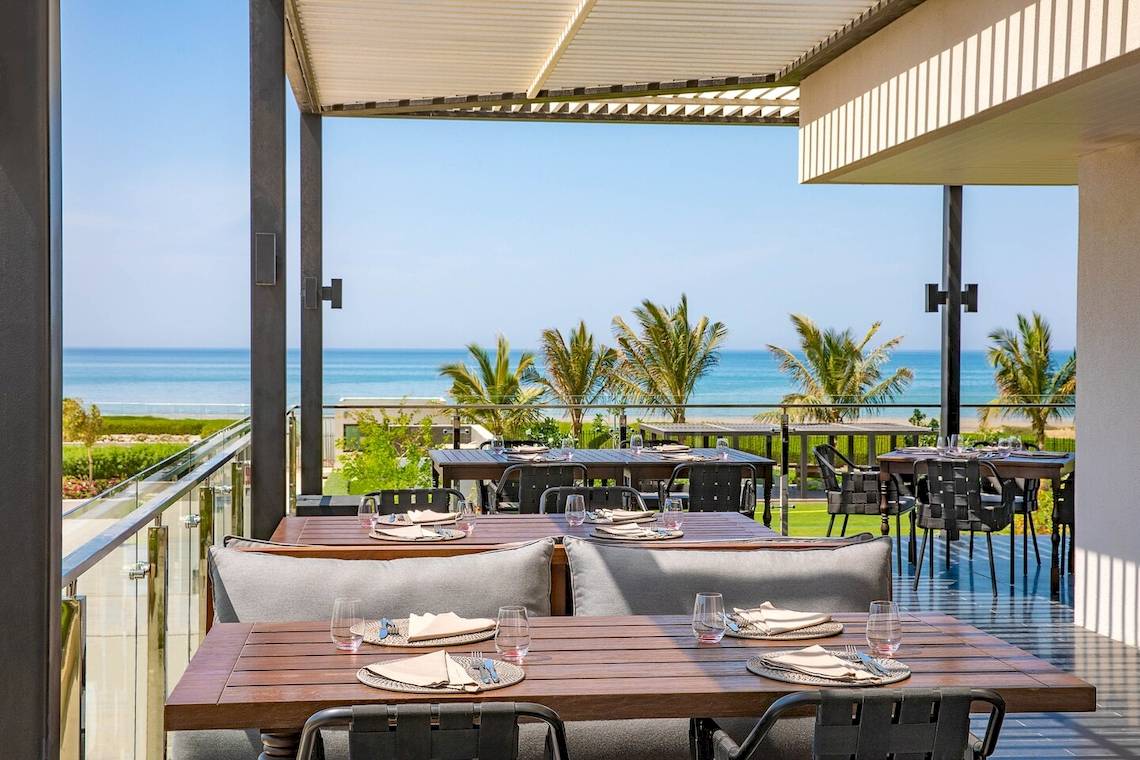 Terrasse des W Muscat Hotels mit Blick auf das Meer und Palmen