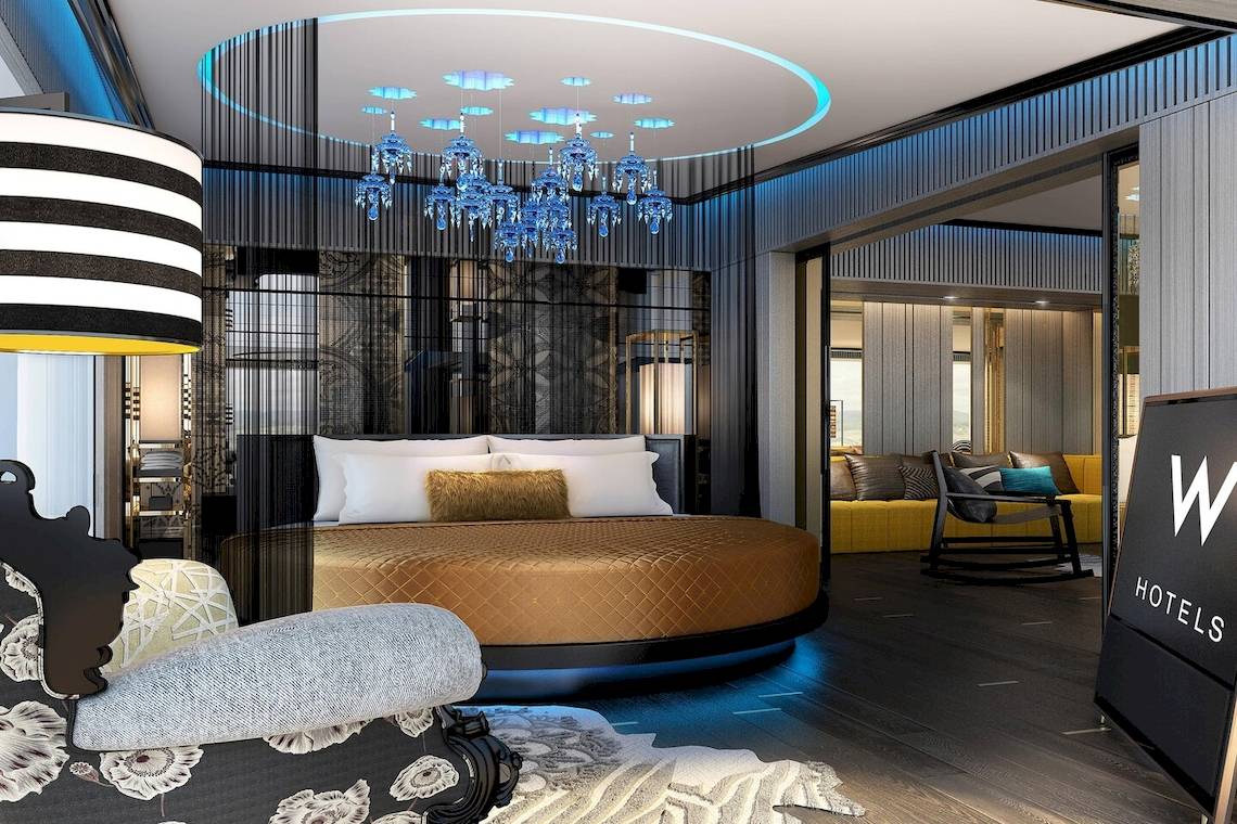 Schlafzimmer im W Muscat Hotel mit Kronleuchter und rundem Bett.