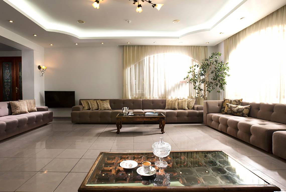 Wohnzimmer mit drei Sofas, einem Couchtisch und einer Lampe, alles in einem hellen Raum