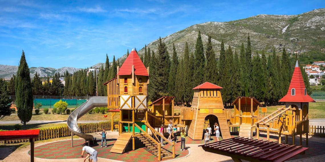 Spielplatz im Freien im Remisens Hotel Albatros mit Holzburgen und Rutsche