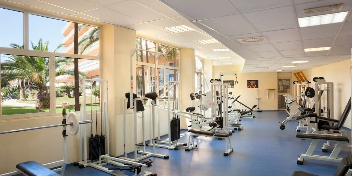 Fitnesscenter im Remisens Hotel Albatros mit verschiedenen Trainingsgeräten und großen Fenstern.