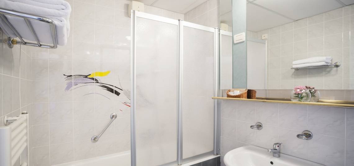 Badezimmer im Remisens Hotel Albatros mit Dusche, Spiegel und Waschbecken.