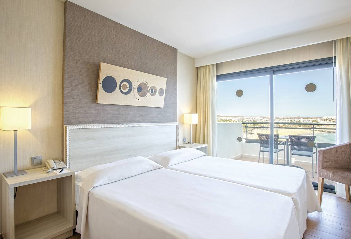 Doppelbettzimmer im Be Live Experience Lanzarote Beach Hotel mit Meerblick und Balkonmöbeln.