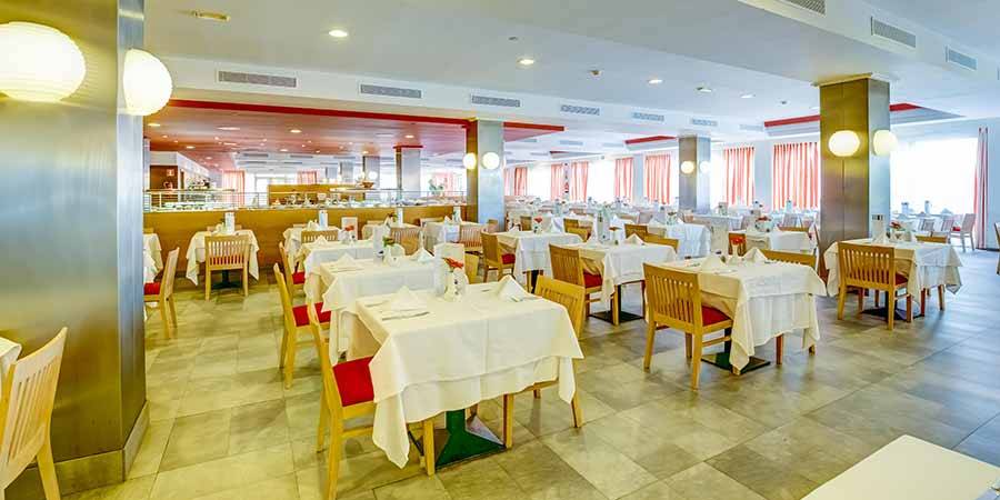 Restaurant im SBH Taro Beach Hotel mit vielen gedeckten Tischen und Stühlen.