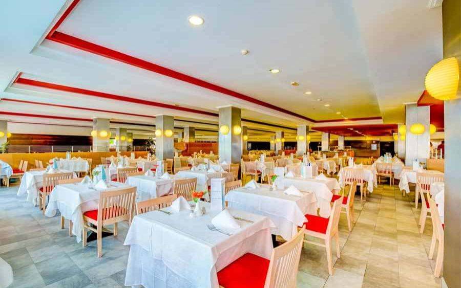 Restaurant im SBH Taro Beach Hotel mit vielen gedeckten Tischen und Stühlen.