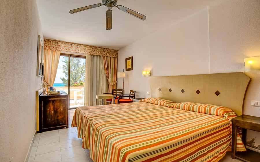 Innenansicht eines Doppelzimmers im SBH Taro Beach Hotel mit Bett, Nachttischen und Aussicht.