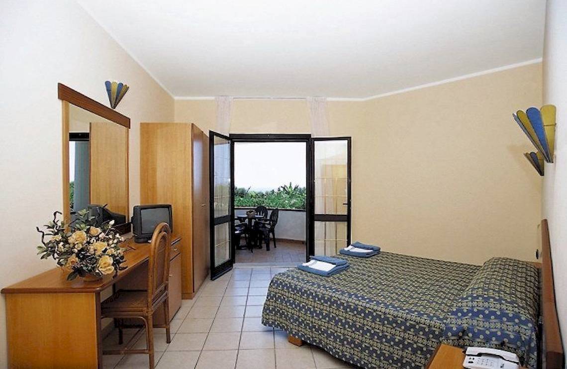 Hotelzimmer mit Balkon, Bett, Schreibtisch und Fernseher.