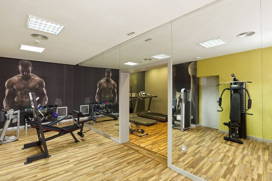 Fitnessstudio im Olympic Palace Resort mit Spiegelwänden und Trainingsgeräten.