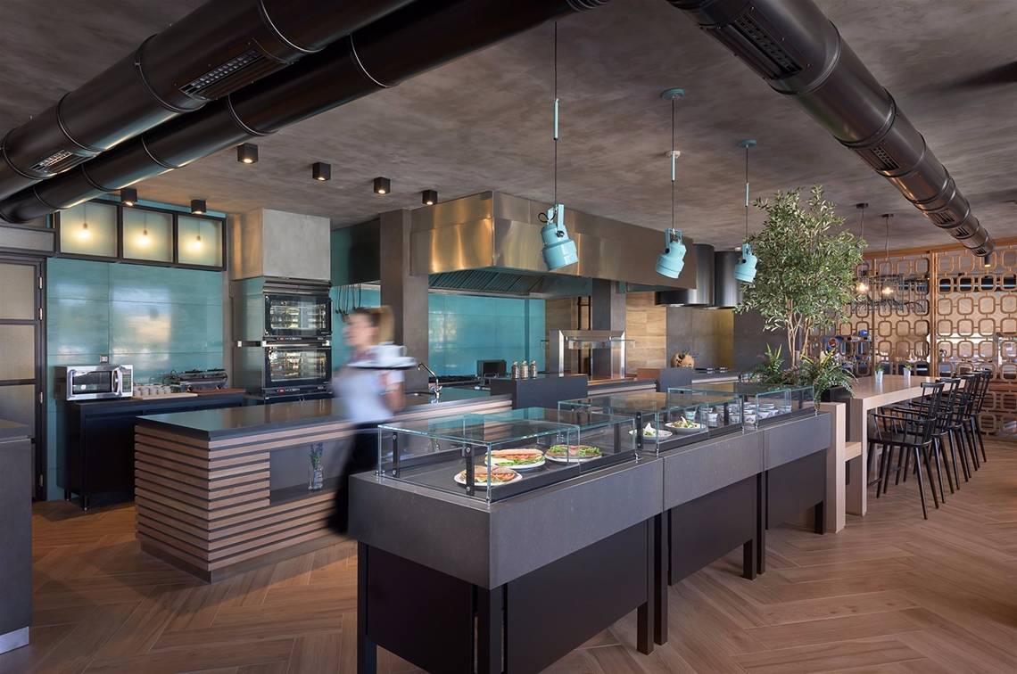 Innenraum des Restaurants im Olympic Palace Resort mit Buffet, Bar und Holzboden.