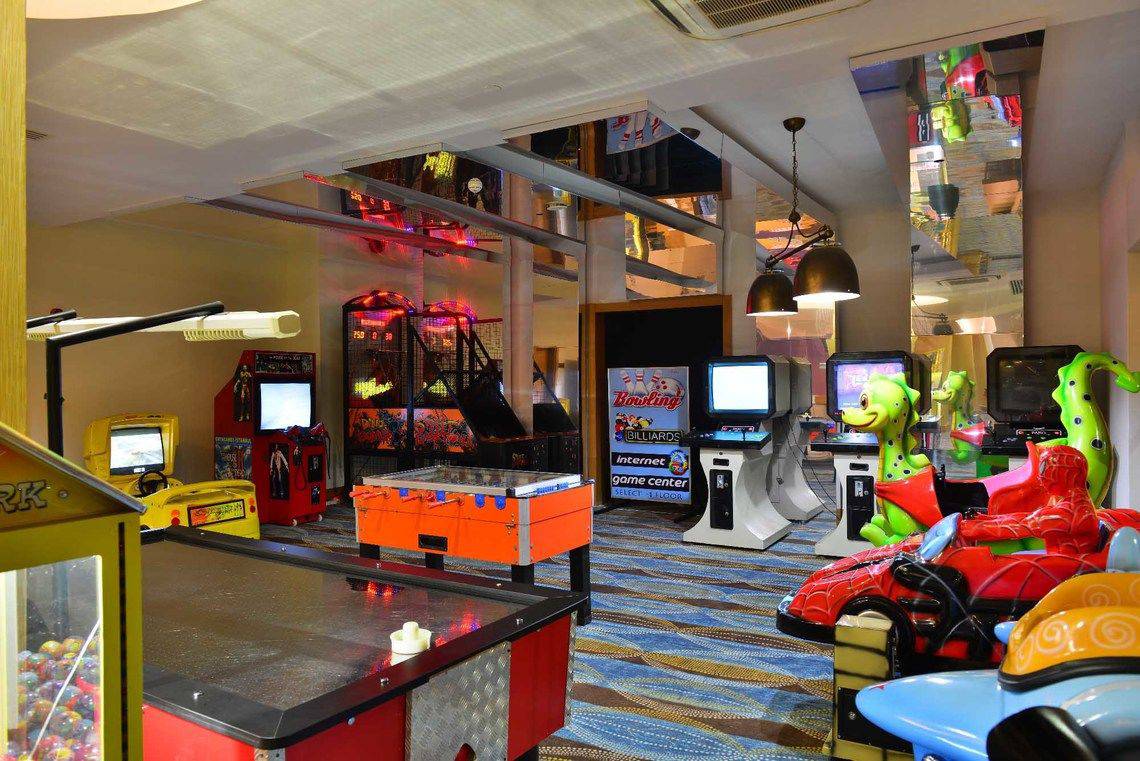 Spielhalle im Side Crown Palace Hotel mit verschiedenen Arcade-Spielen und bunten Dekorationen.