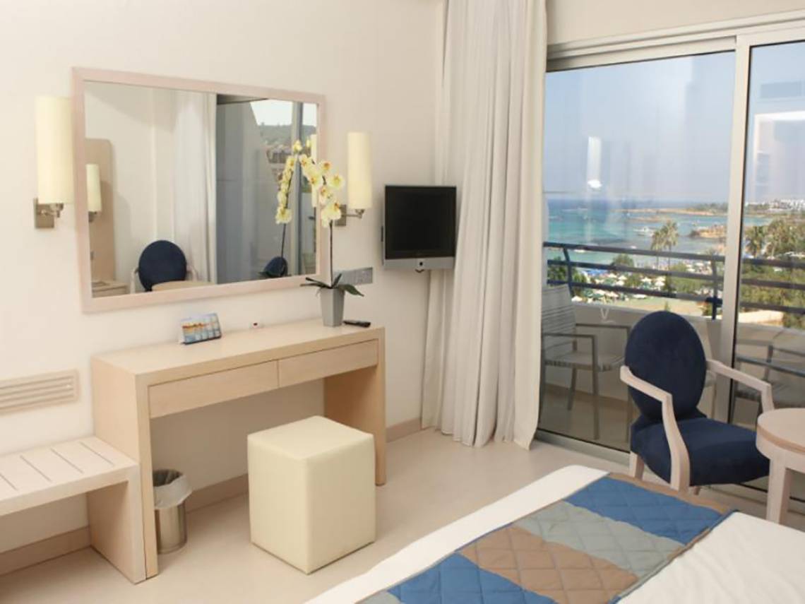 Vrissiana Beach Hotelzimmer mit Meerblick, Spiegel, Fernseher und Balkon.