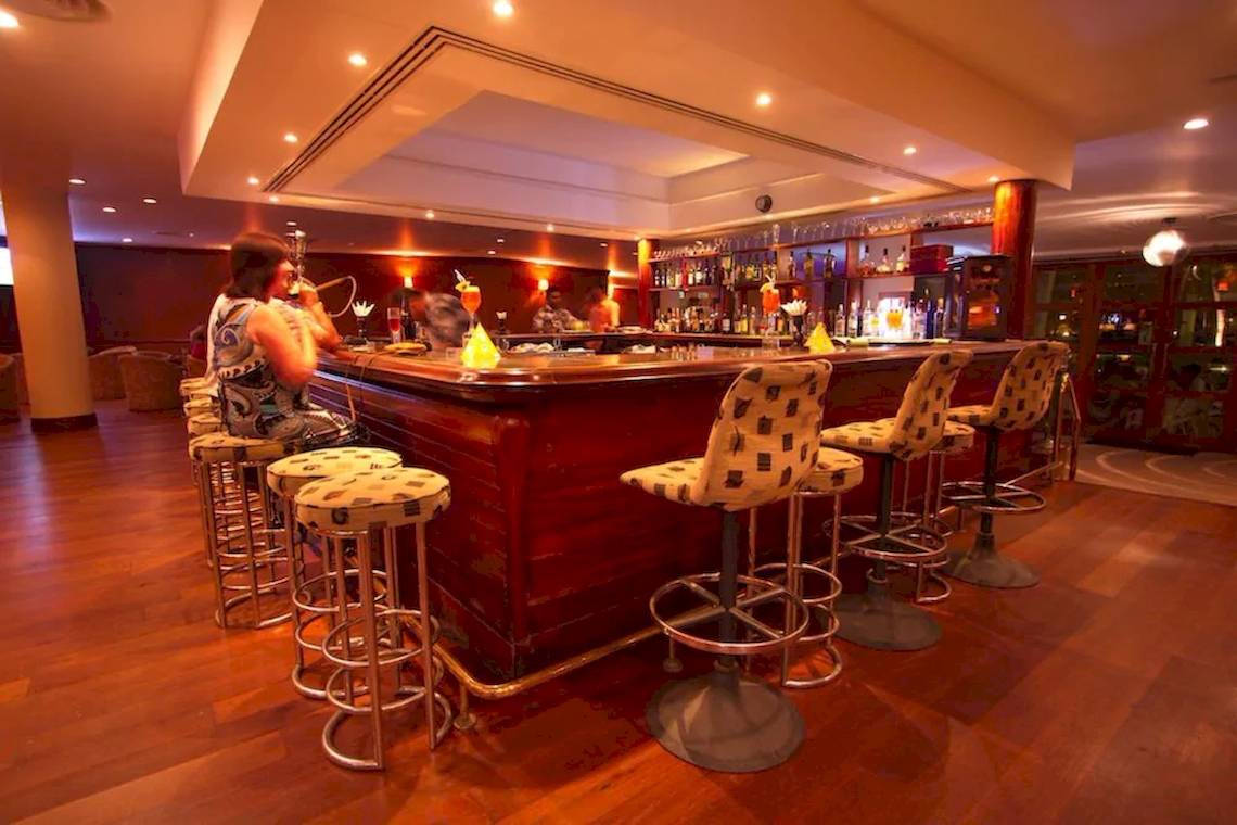 Bar des Occidental Eden Beruwala Hotels mit rauchender Frau und Cocktails.