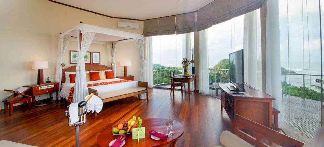 Luxuriöse Suite im Occidental Eden Beruwala mit Blick auf das Meer, einem großen Bett und einer Terrasse.