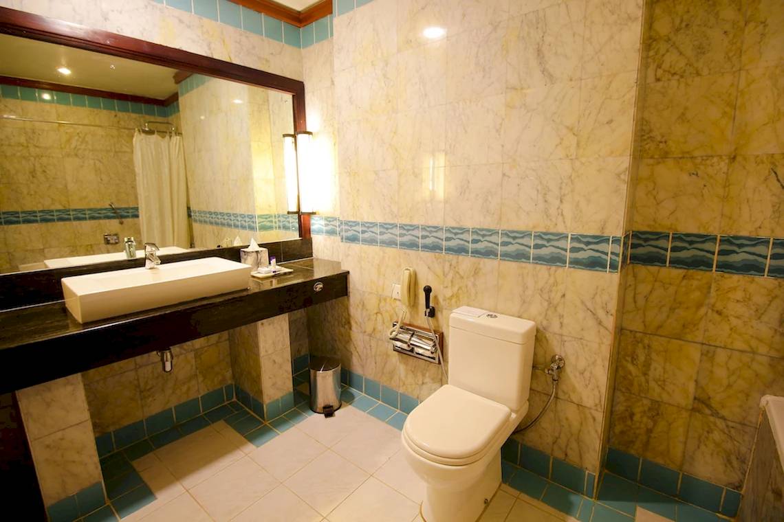 Badezimmer im Occidental Eden Beruwala Hotel mit Waschbecken, Spiegel und Toilette.