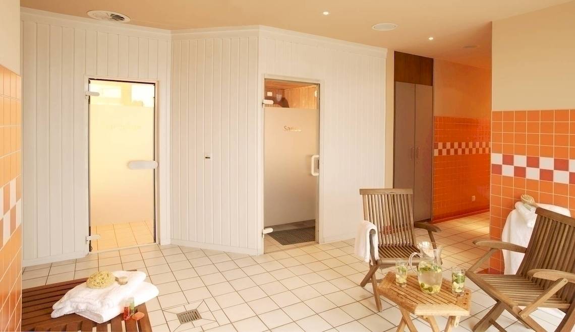 Saunabereich im NH Hamburg Altona Hotel mit weißen und orangefarbenen Fliesen.
