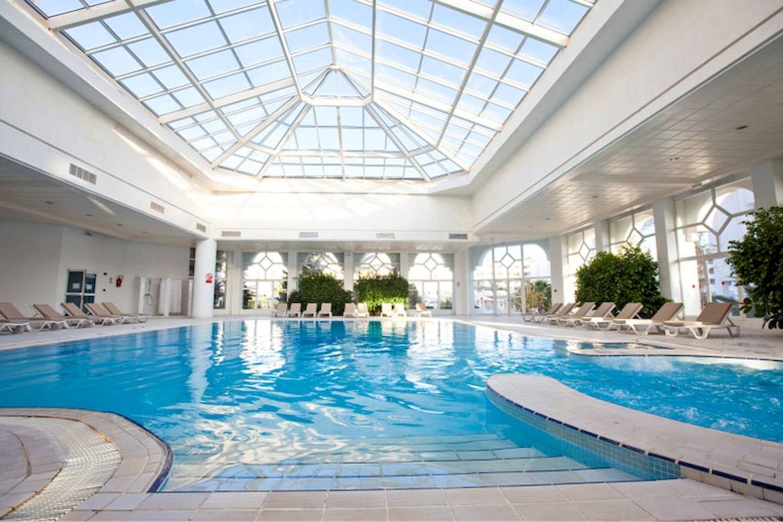 Innenpool des El Mouradi Hammamet Hotels mit Glasdach und Loungeliegen