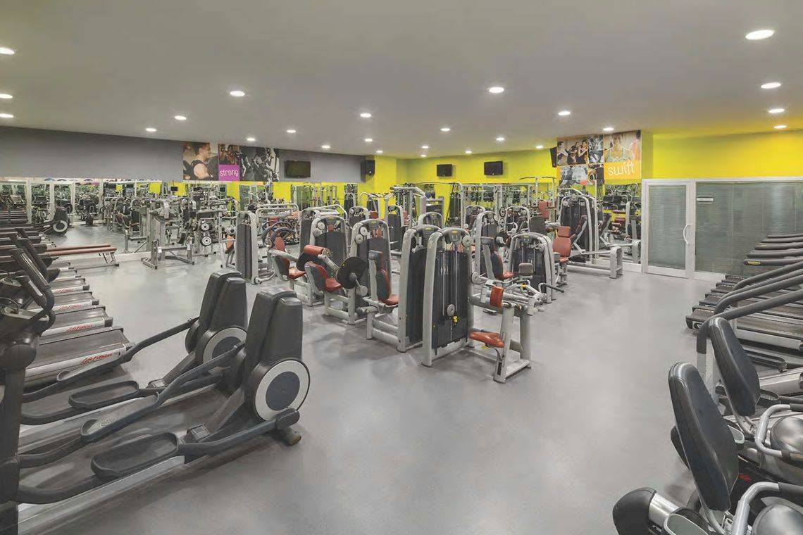 Fitnesscenter des Wyndham Grand Izmir Ozdilek Hotels mit vielen Geräten und gelben Wänden.