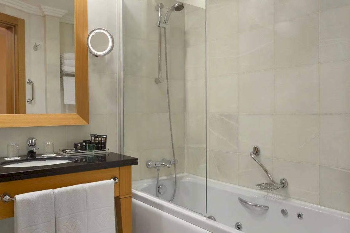 Badezimmer im Wyndham Grand Izmir Ozdilek Hotel mit Badewanne, Spiegel und Waschbecken.
