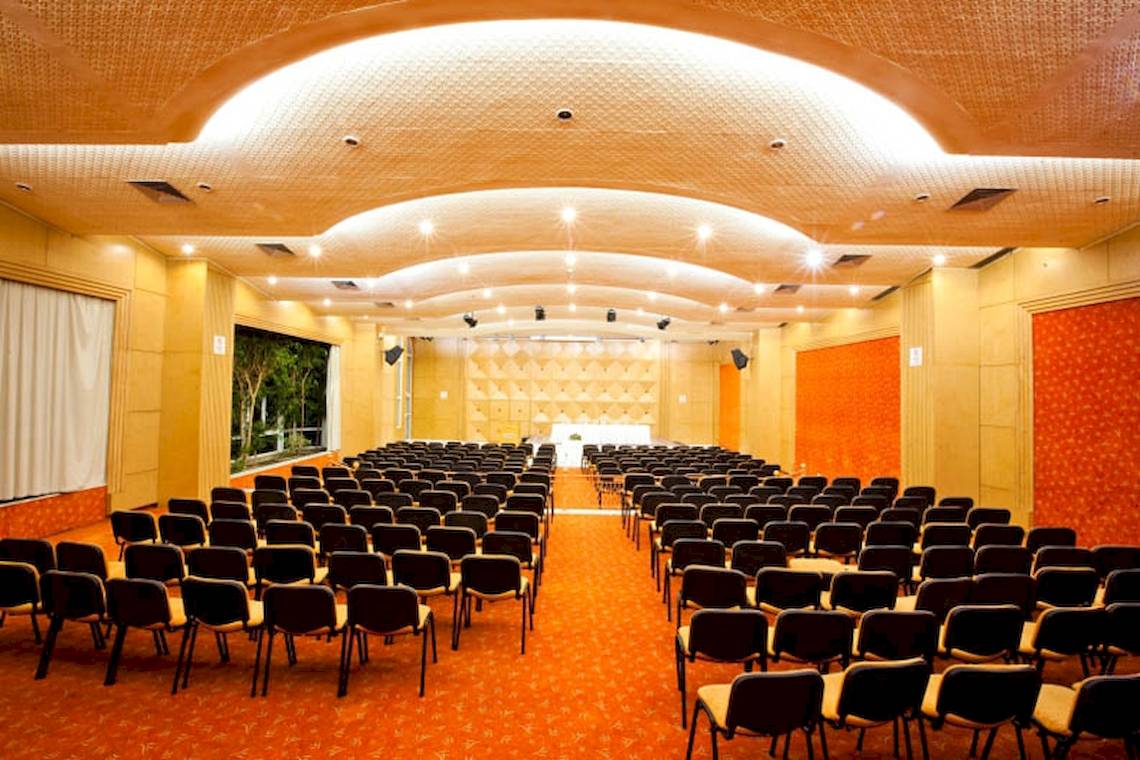 Ein Konferenzraum im El Mouradi Hammamet Hotel mit Reihen von Stühlen und einer Bühne.