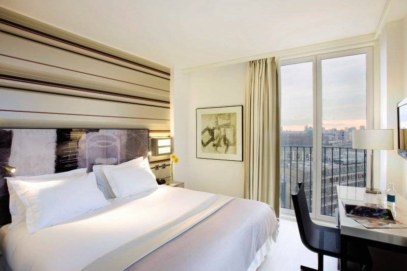 H10 London Waterloo Hotelzimmer mit Bett, Schreibtisch und Blick auf die Stadt.