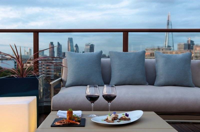 Aussicht auf die Londoner Skyline von der Terrasse des H10 London Waterloo Hotels mit Gerichten und Getränken.