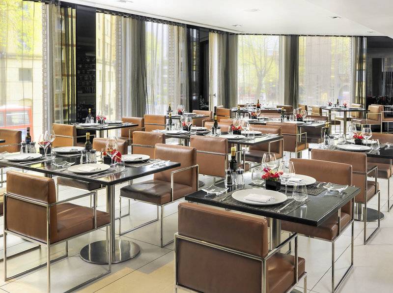 Foto des Innenbereichs des Restaurants im H10 London Waterloo Hotel mit gedeckten Tischen und Stühlen.