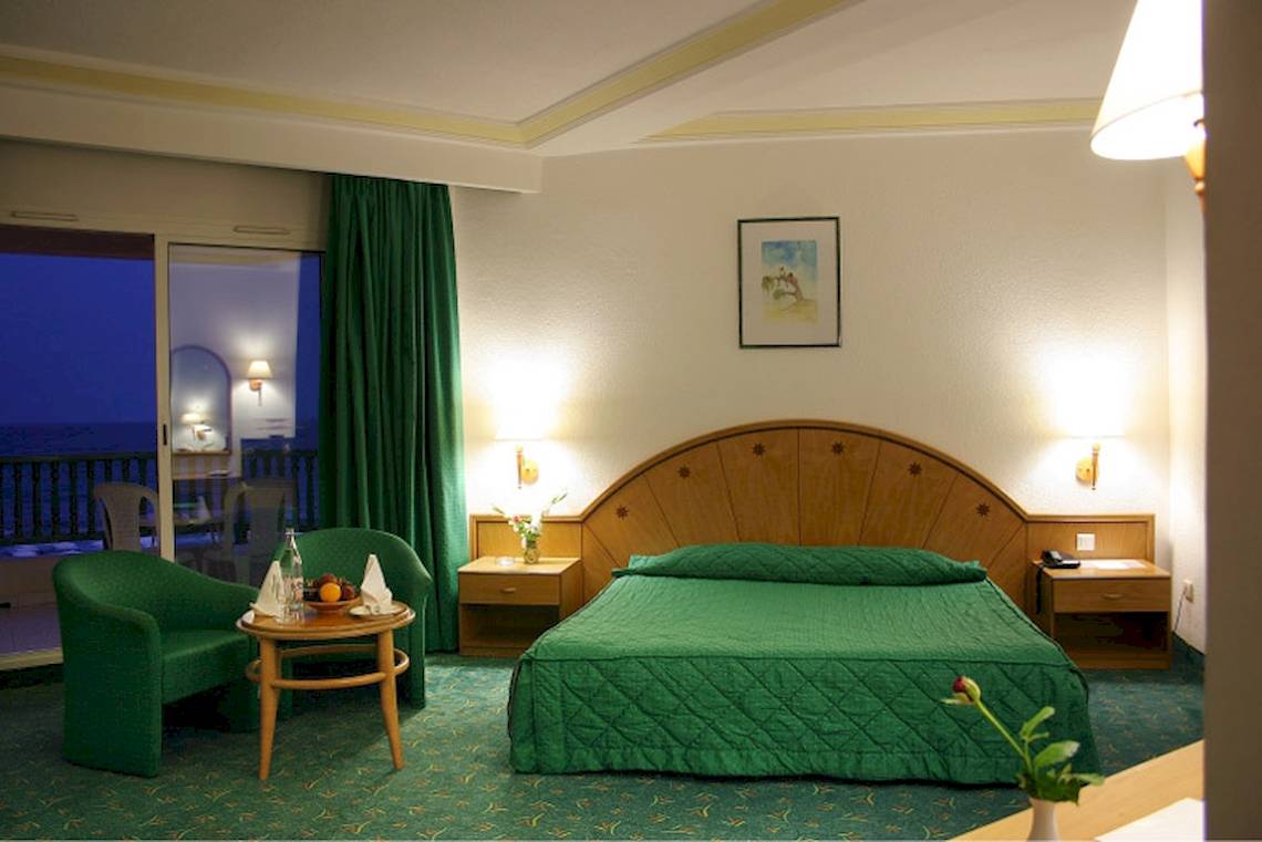 Grünes Zimmer im El Mouradi Hammamet Hotel mit Bett, Stühlen und Aussicht auf den Balkon