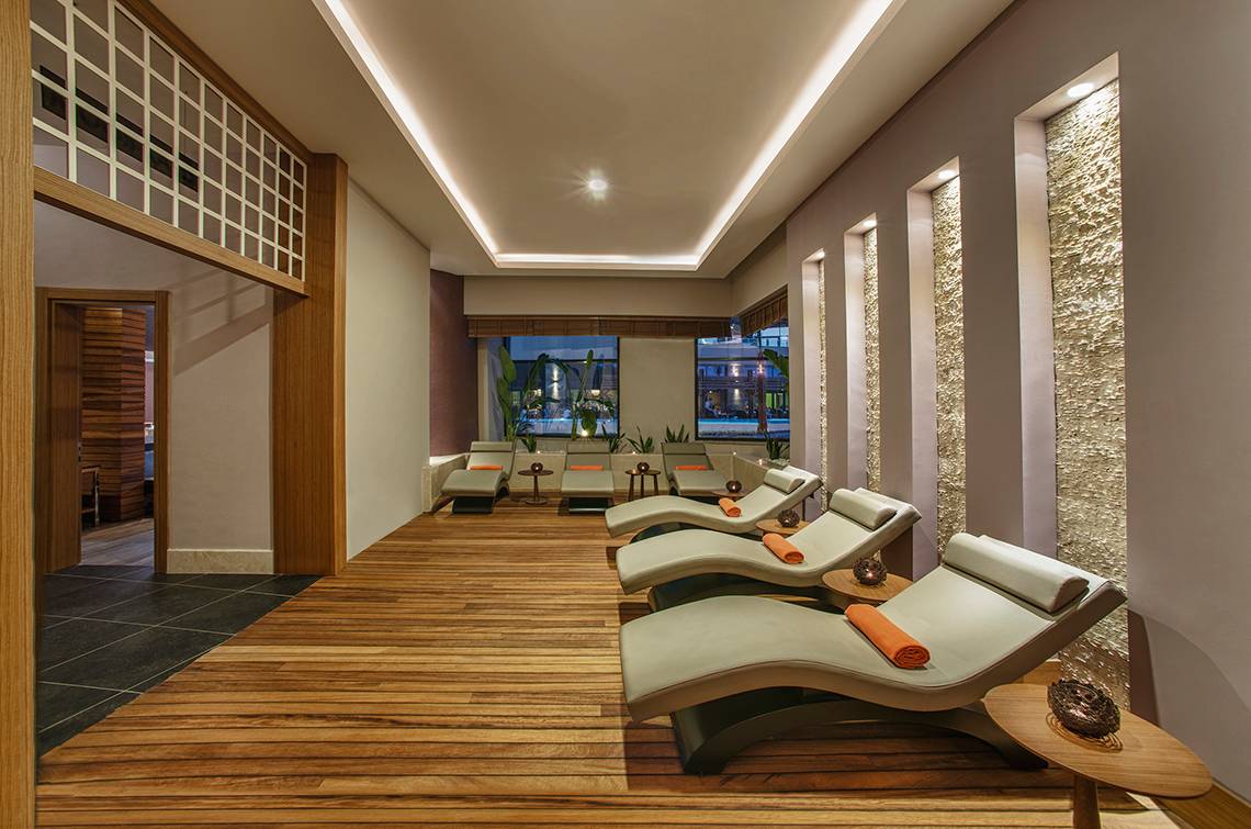 Loungebereich im Aska Lara Resort & Spa mit Holzboden und modernen Liegestühlen.