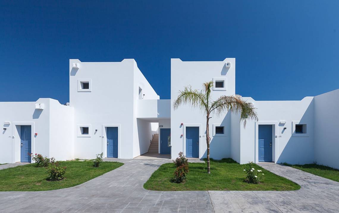 Außenansicht des Aeolos Beach Hotel auf Kos mit weißen Gebäuden und blauen Türen.
