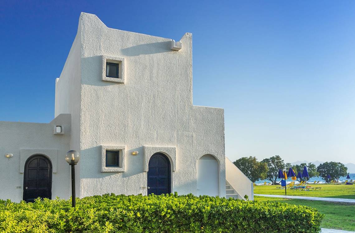 Außenansicht des Aeolos Beach Hotel auf Kos mit weißen Wänden und einer ruhigen Umgebung.
